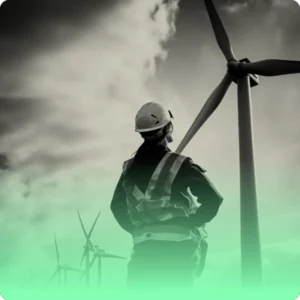 a technician in a hard hat looks at a wind turbine